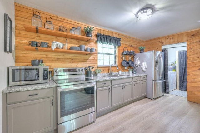 kitchen with stainless steel appliances, gray cabinetry, a sink, open shelves, and light wood-style floors