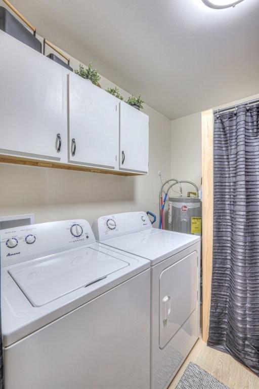 laundry area with separate washer and dryer, electric water heater, and cabinet space
