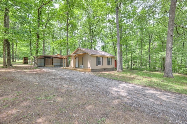 view of front of property with a carport, dirt driveway, crawl space, and an outbuilding