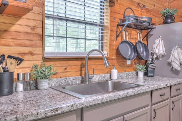 kitchen view of a sink, light countertops, and wood walls