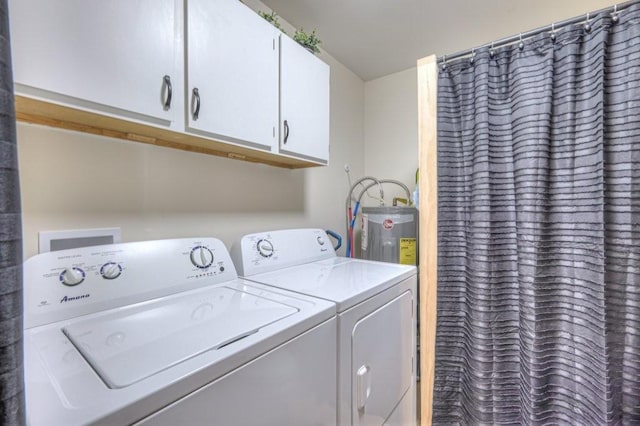 laundry room featuring washer and dryer, electric water heater, and cabinet space