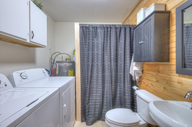 bathroom with separate washer and dryer, electric water heater, a sink, and toilet