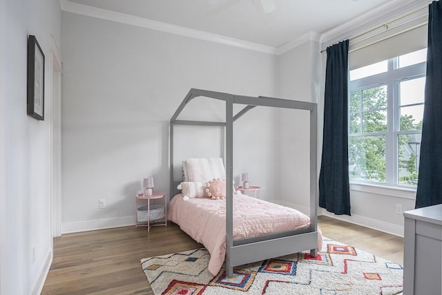 bedroom featuring ornamental molding, light wood-style flooring, and baseboards