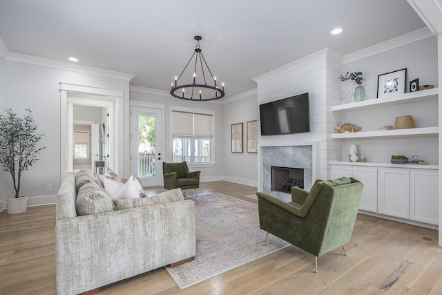 living room with ornamental molding, a chandelier, baseboards, a high end fireplace, and recessed lighting