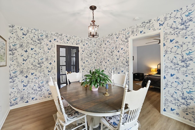 dining space featuring wallpapered walls, light wood-style floors, and baseboards