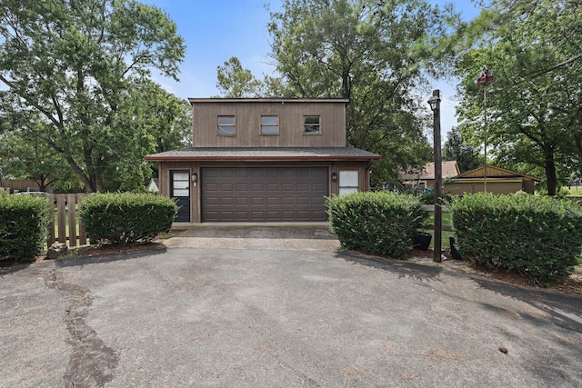 garage featuring driveway and fence