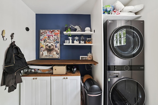 clothes washing area with stacked washer / dryer and cabinet space