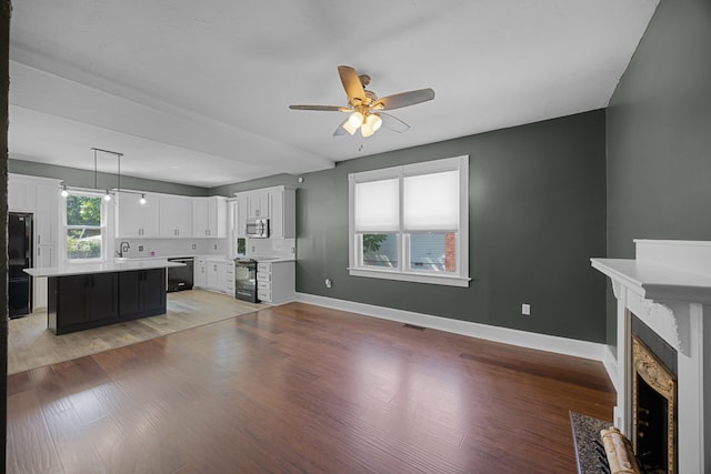 321 Head St, Paris, TN 38242 - unfurnished living room with a fireplace with flush hearth, ceiling fan, baseboards, and light wood-style floors