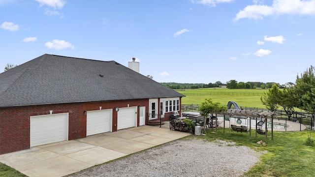 4484 N Pinson Rd, Portland, TN 37148 - view of side of property with a shingled roof, a garage, concrete driveway, a chimney, and brick siding