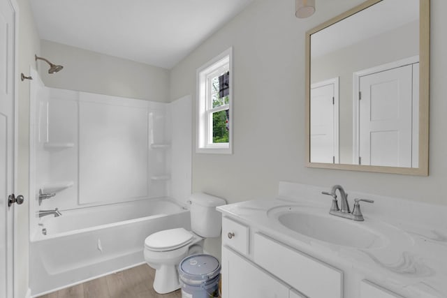 bathroom featuring toilet, wood finished floors, vanity, and tub / shower combination