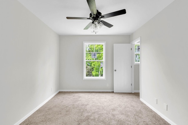 carpeted empty room featuring a ceiling fan and baseboards