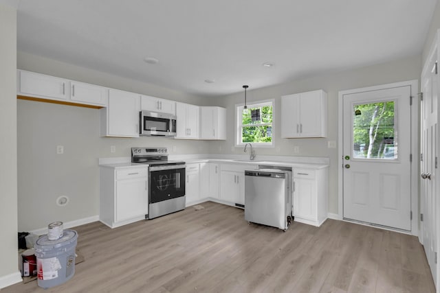 kitchen featuring stainless steel appliances, a sink, light countertops, and light wood finished floors