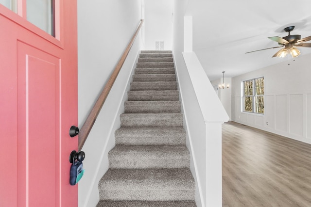 stairs with wood finished floors and a ceiling fan