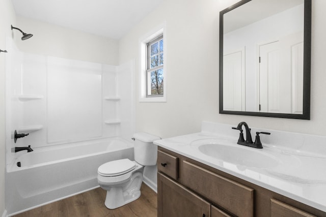 bathroom featuring toilet, wood finished floors, vanity, shower / bathtub combination, and baseboards