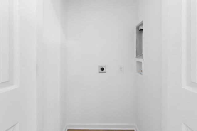 clothes washing area with electric dryer hookup, hookup for a washing machine, wood finished floors, and baseboards