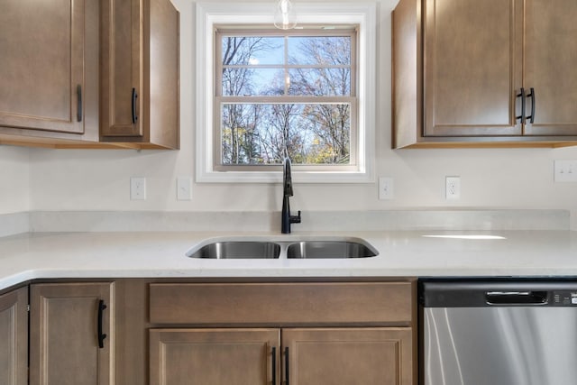kitchen with stainless steel dishwasher, a sink, and light countertops
