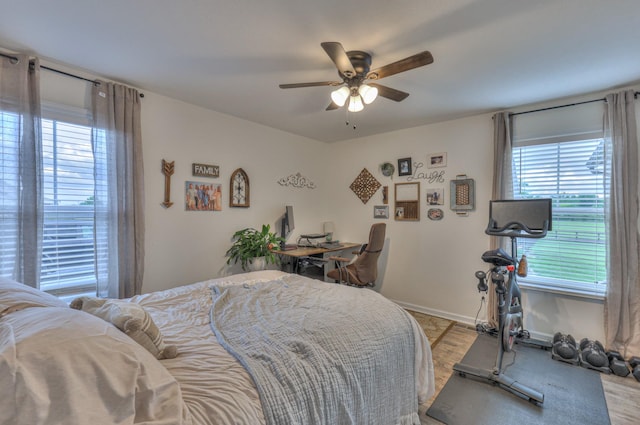 bedroom featuring multiple windows, light wood-style floors, baseboards, and a ceiling fan