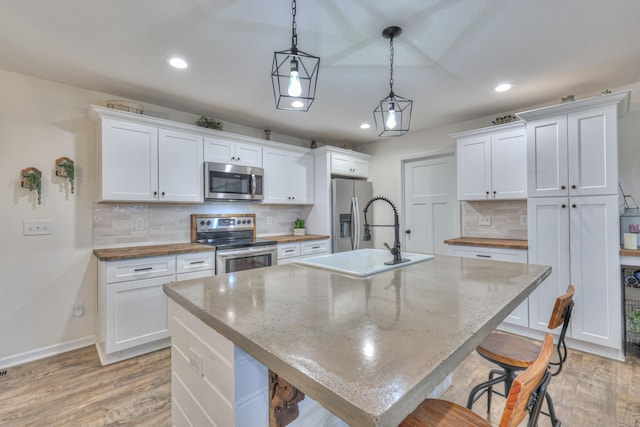 kitchen with appliances with stainless steel finishes, a sink, recessed lighting, white cabinets, and decorative backsplash