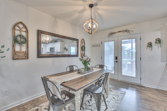 dining space with a chandelier, wood finished floors, and baseboards