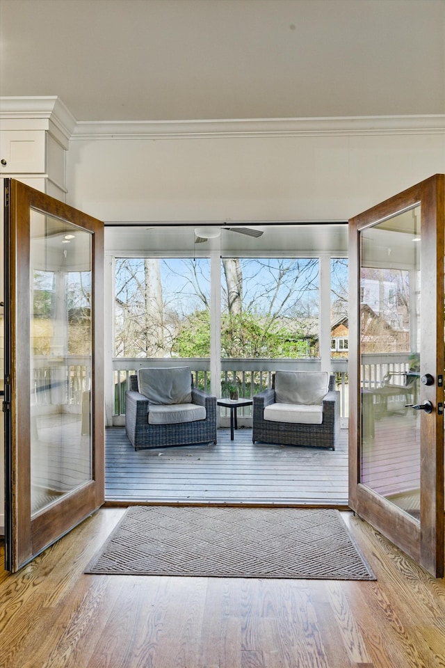 entryway with wood finished floors, ornamental molding, and plenty of natural light