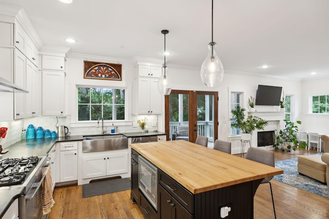 kitchen with butcher block countertops, open floor plan, a sink, white cabinets, and recessed lighting