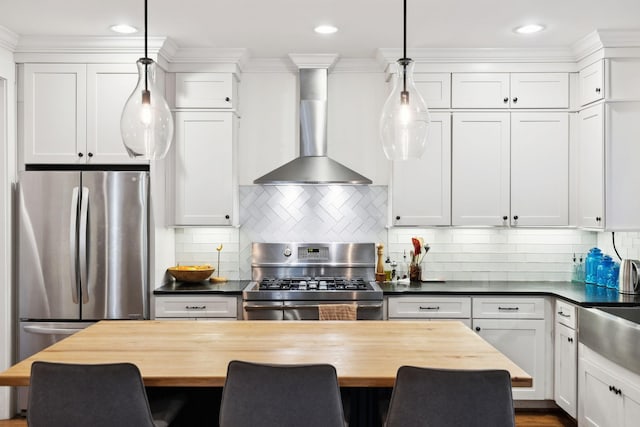 kitchen featuring stainless steel appliances, wall chimney range hood, white cabinets, butcher block counters, and recessed lighting