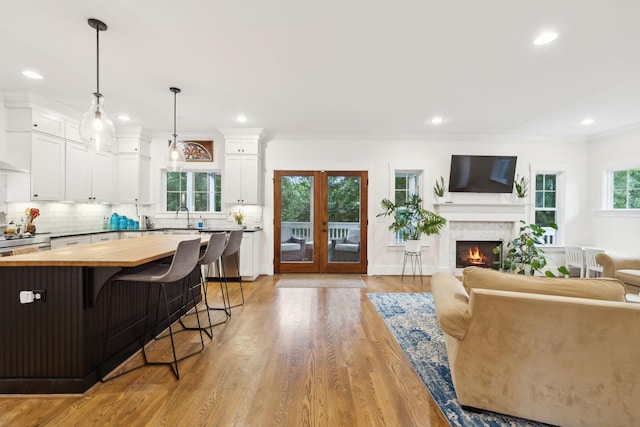 kitchen with butcher block counters, a breakfast bar area, white cabinets, open floor plan, and recessed lighting