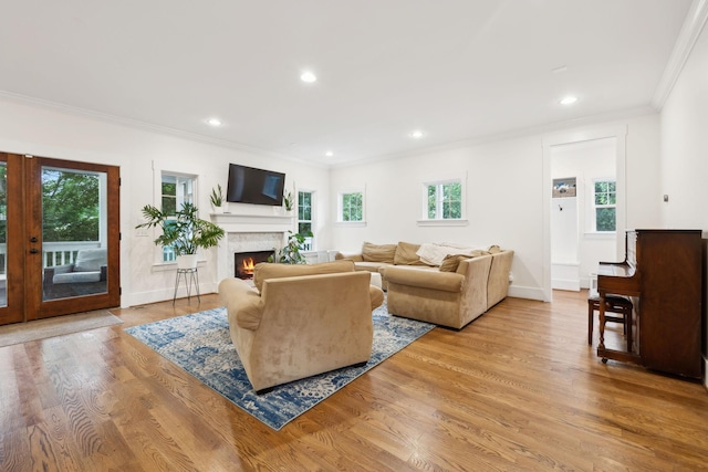 living room featuring crown molding, a warm lit fireplace, wood finished floors, recessed lighting, and french doors