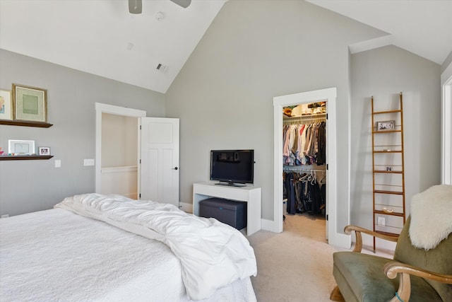 bedroom featuring a walk in closet, light carpet, a closet, high vaulted ceiling, and baseboards