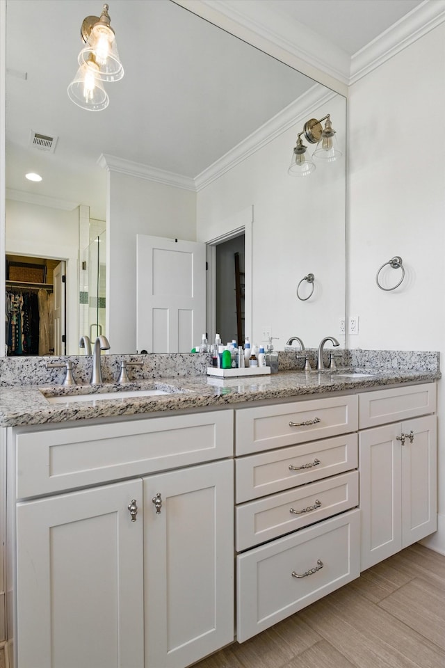 bathroom featuring crown molding, double vanity, wood finished floors, a spacious closet, and a shower with shower door