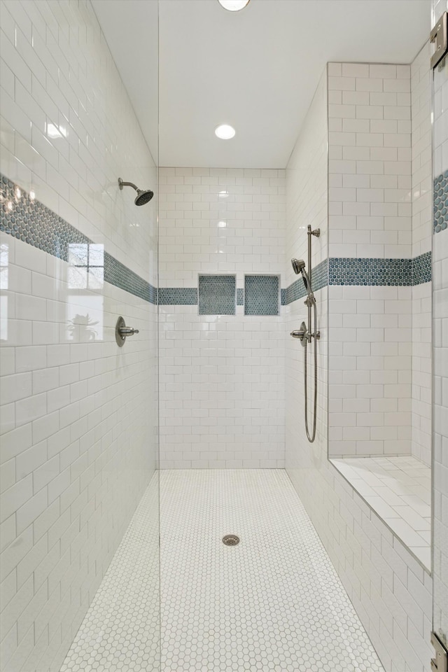 full bath featuring tiled shower and tile patterned flooring