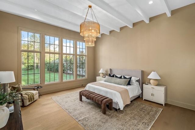 bedroom featuring beam ceiling, multiple windows, a chandelier, wood finished floors, and baseboards