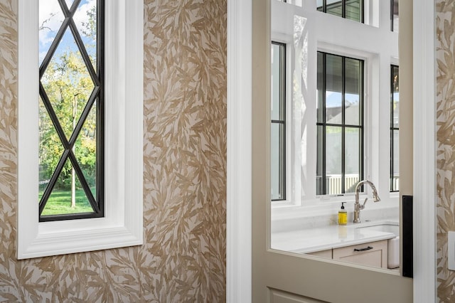 bathroom with wallpapered walls and a sink