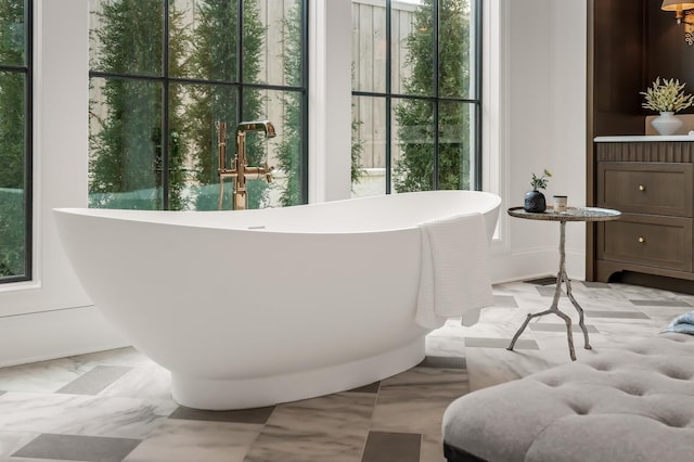 bathroom with marble finish floors and a soaking tub