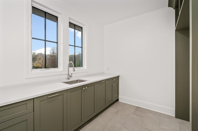 kitchen with a sink, baseboards, and light countertops