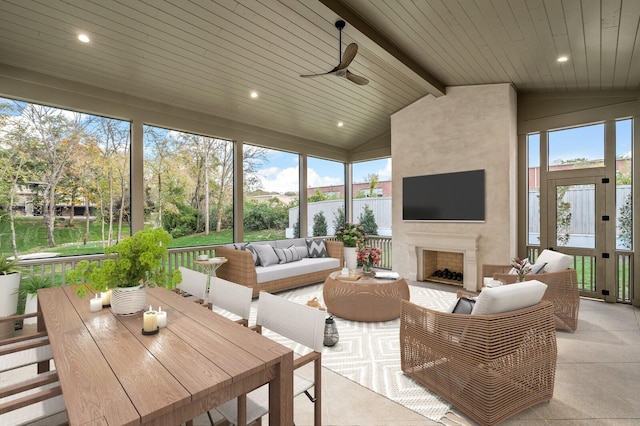 sunroom featuring an outdoor living space with a fireplace, ceiling fan, healthy amount of natural light, and outdoor dining area