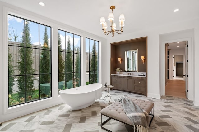 bathroom featuring plenty of natural light, vanity, a freestanding tub, a chandelier, and recessed lighting