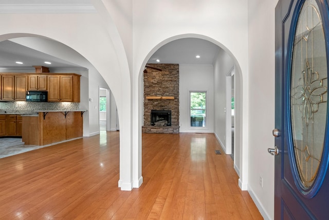 entrance foyer featuring light wood-type flooring, a stone fireplace, baseboards, and recessed lighting