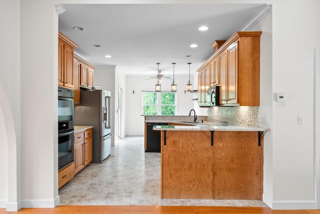 kitchen featuring a peninsula, a sink, black appliances, a ceiling fan, and a breakfast bar area