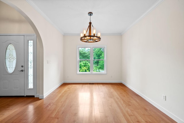 entrance foyer featuring arched walkways, a chandelier, light wood finished floors, ornamental molding, and baseboards