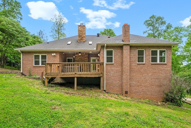 back of property with a wooden deck, a lawn, brick siding, and a chimney