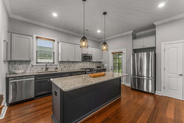 kitchen with stainless steel appliances, a sink, decorative backsplash, light stone counters, and a center island
