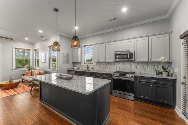kitchen with stainless steel appliances, a center island, decorative backsplash, a sink, and recessed lighting