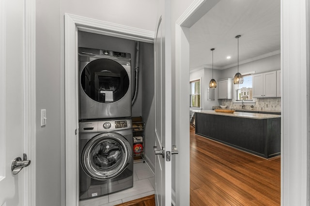 washroom featuring stacked washer / dryer and ornamental molding