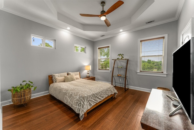 bedroom with wood finished floors, a raised ceiling, crown molding, baseboards, and recessed lighting