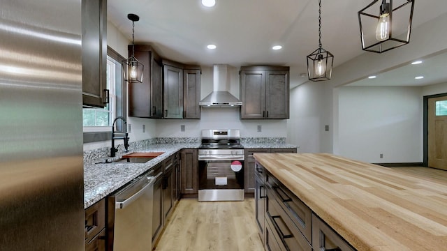 2038 Ogburn Chapel Rd, Clarksville, TN 37042 - kitchen featuring wall chimney exhaust hood, appliances with stainless steel finishes, a sink, light wood finished floors, and dark brown cabinets