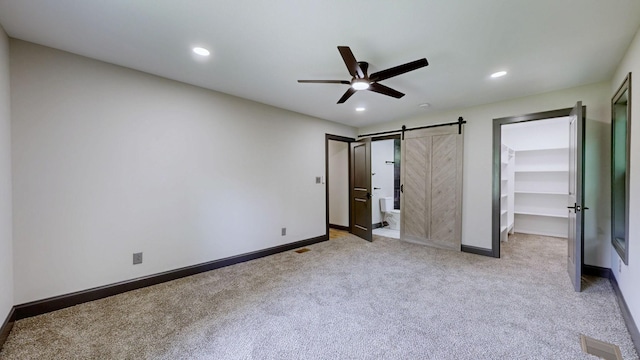 2038 Ogburn Chapel Rd, Clarksville, TN 37042 - unfurnished bedroom featuring a barn door, light carpet, a walk in closet, baseboards, and recessed lighting