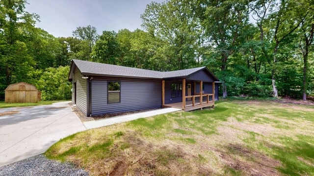 2038 Ogburn Chapel Rd, Clarksville, TN 37042 - view of front facade with covered porch, an outdoor structure, a shed, a front lawn, and roof with shingles