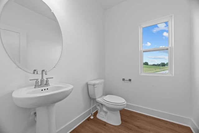 half bath featuring wood finished floors, baseboards, and toilet