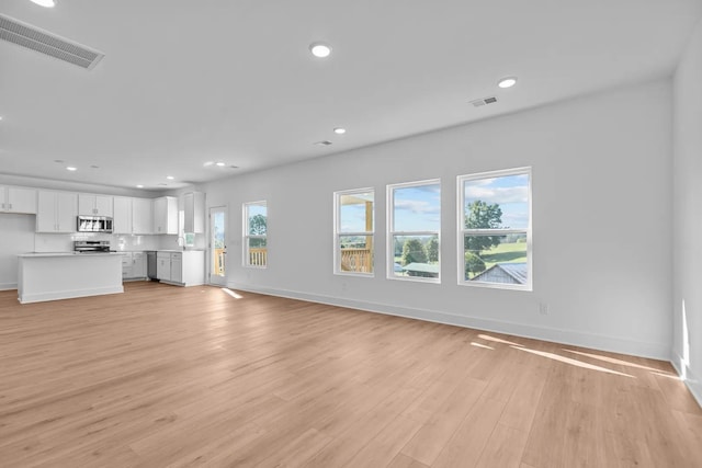 unfurnished living room featuring light wood finished floors, baseboards, and recessed lighting